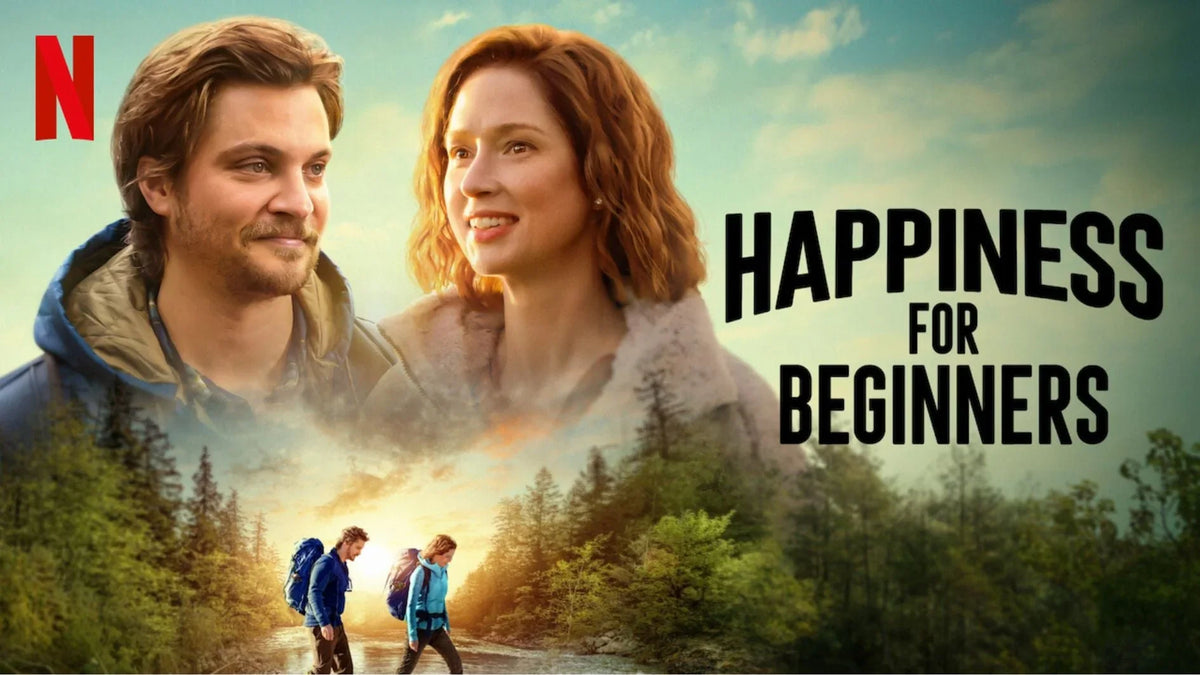 Official poster for Netflix's Happiness for Beginners featuring Luke Grimes and Ellie Kemper above a scenic forest landscape.